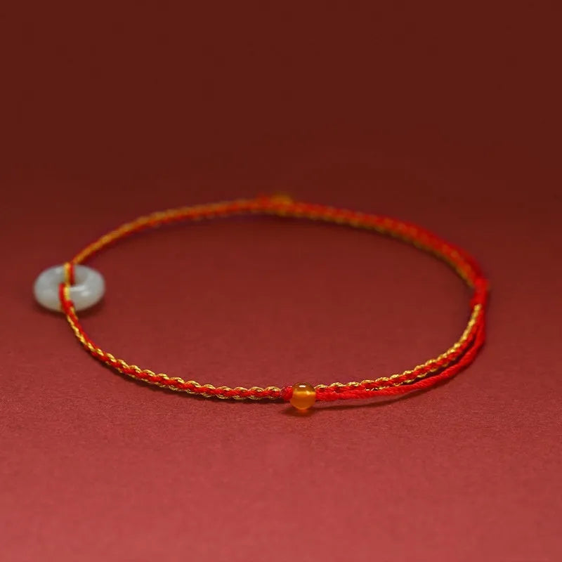 Red rope braided bracelet with natural wave-shaped Hetian jade pendant for Tiger Year birth year, on a neutral background