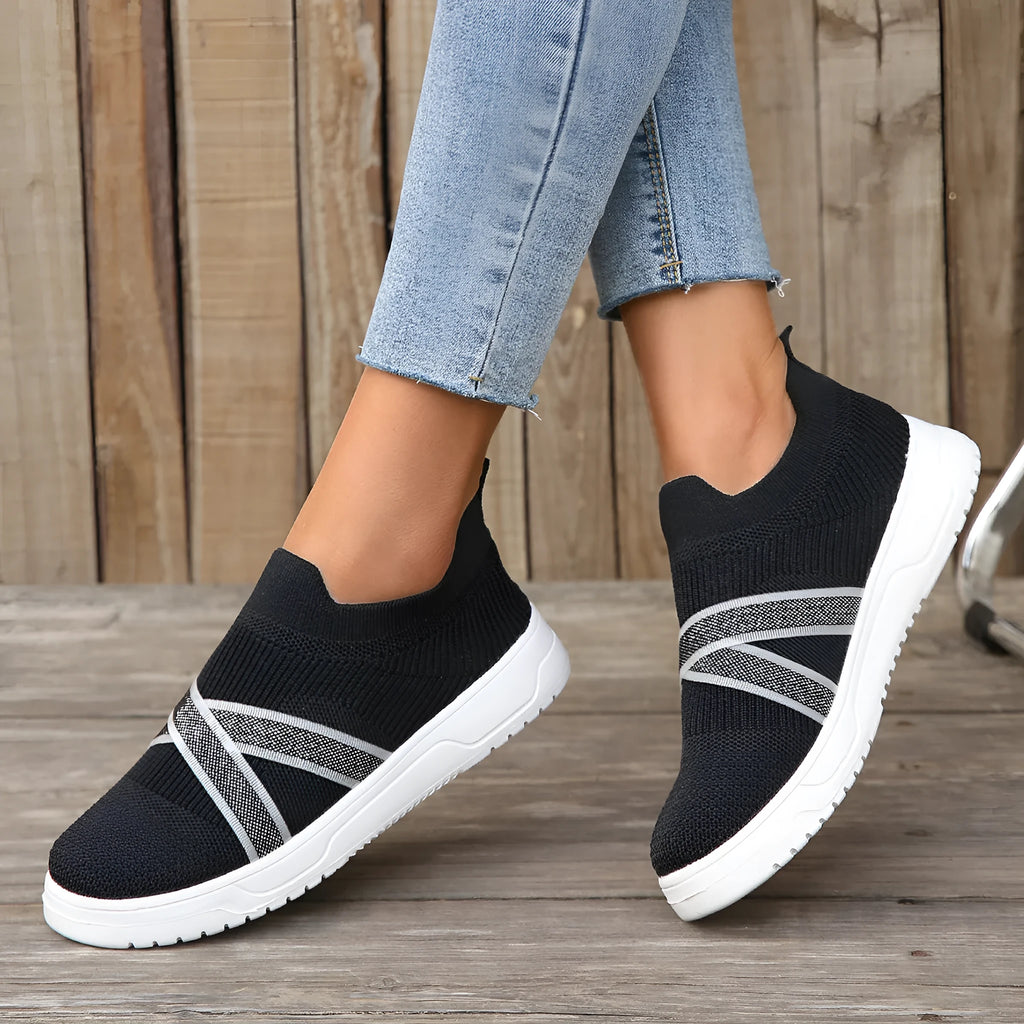 Black women's casual trainers with flyknit mesh upper, flat rubber sole, round toe, and a tassel detail.
