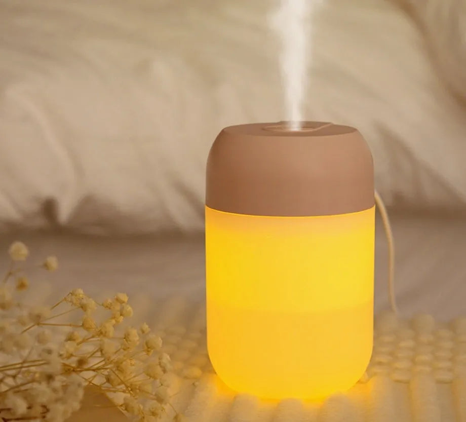 White cylindrical USB mini humidifier on desk with charging cable