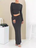 Women's black two-piece autumn suit with exposed navel top and long skirt.