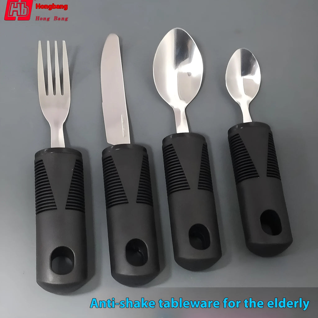 Stainless steel adaptive knife, fork, and spoon set with black rubber handles on a table.