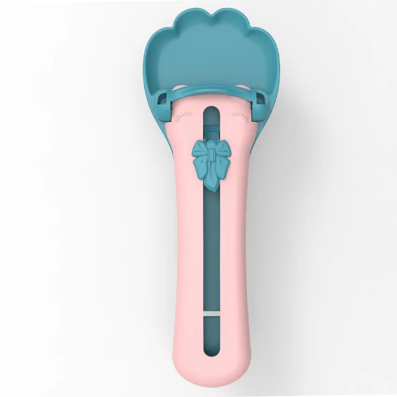 Green and pink pet food squeezer feeder with attached spoon for dispensing liquid and dry food