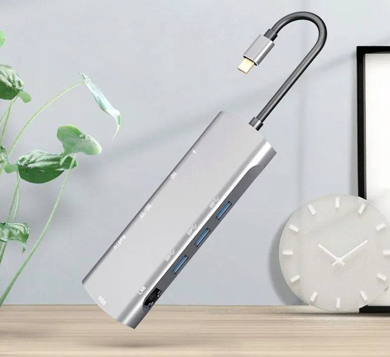 Grey aluminium USB-C docking station with HDMI, VGA, USB ports, and a short cable.