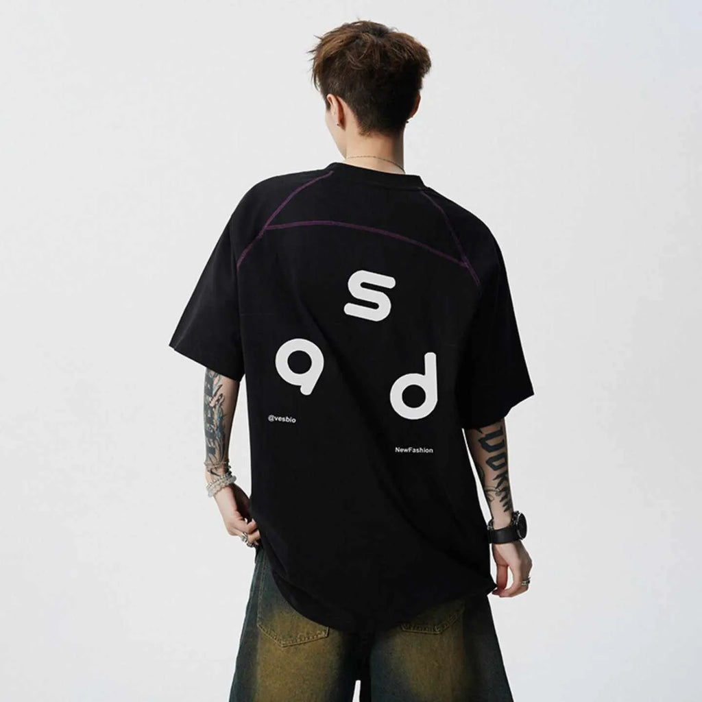 Man wearing a black loose-fit cotton t-shirt with a white letter print on the front.