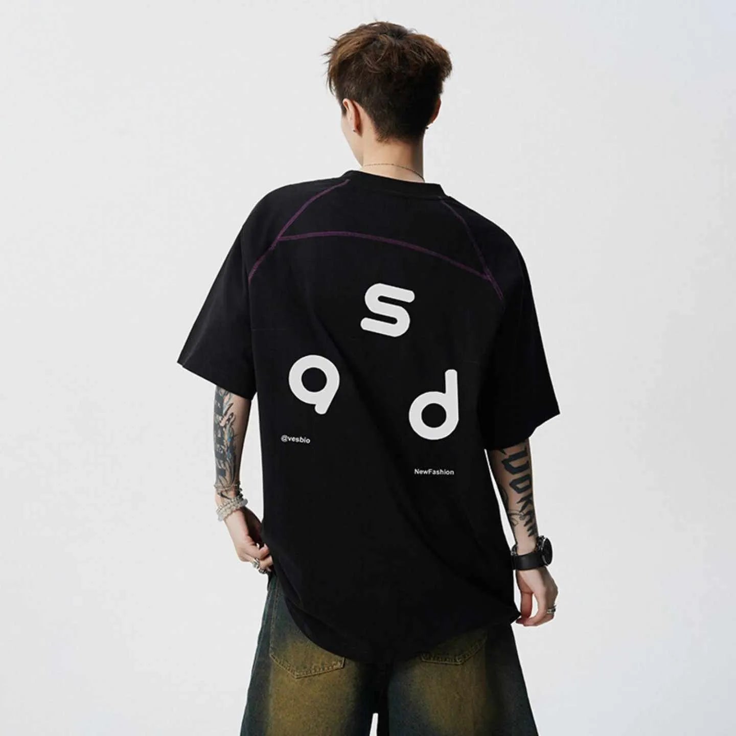 Man wearing a black loose-fit cotton t-shirt with a white letter print on the front.