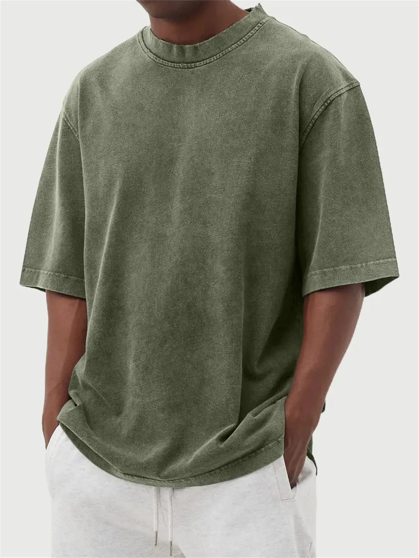 Man wearing a loose-fit, stone-washed polyester T-shirt in a solid colour with a distressed finish.