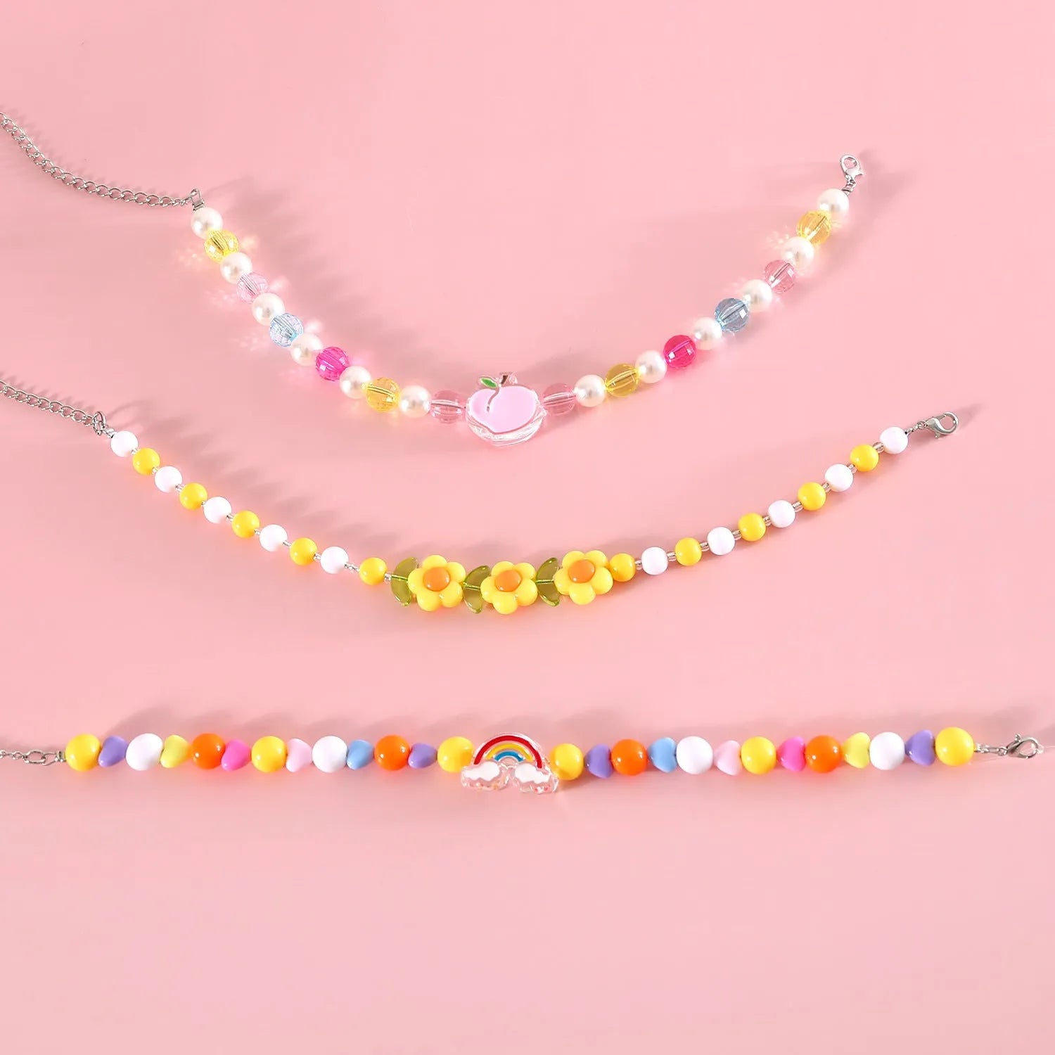 Colourful plastic bead cat necklace in rainbow, peach, or small flower pattern on a white background.