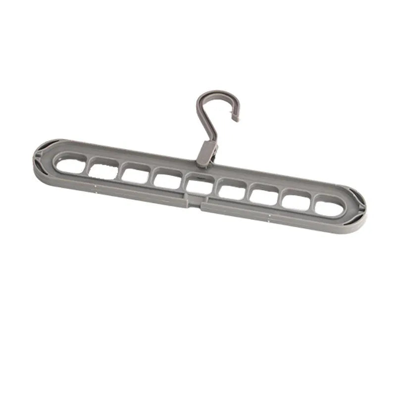 Green plastic folding clothes hanger with nine holes for organising trousers on a rack.