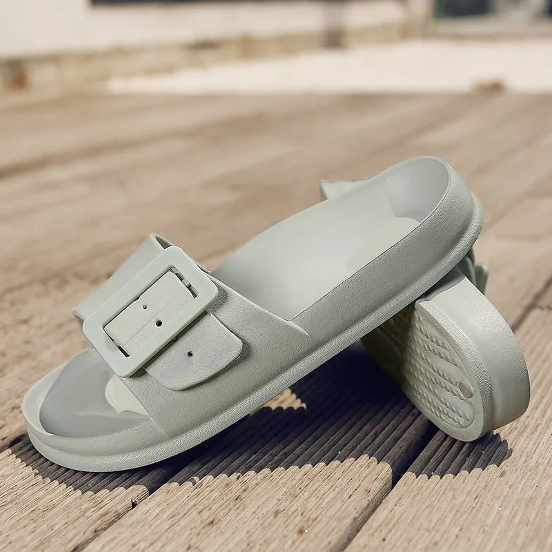 Women's grey blue buckle flip flops with a soft EVA sole on a plain background