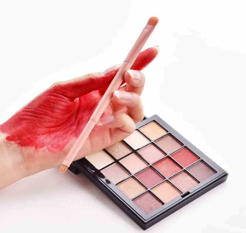 Ten professional makeup brushes with wooden handles arranged by size for different cosmetic applications