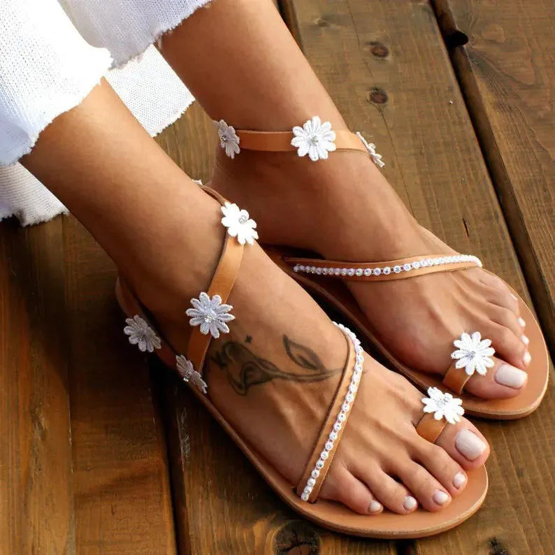 Brown women's Roman sandals with flower detail and herringbone toe design on flat rubber sole