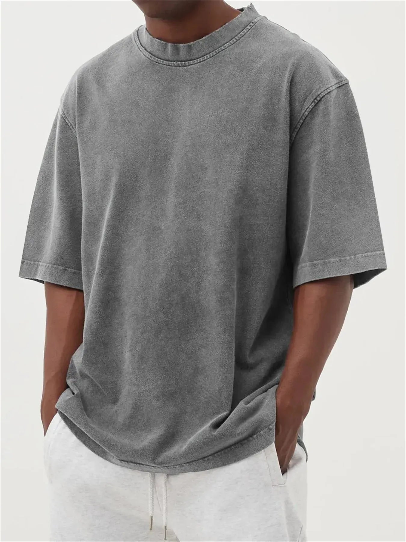 Man wearing a loose-fit, stone-washed polyester T-shirt in a solid colour with a distressed finish.