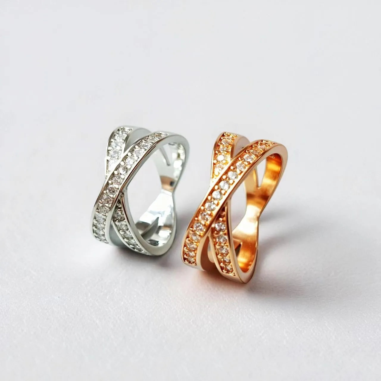 Geometric cross design ring with micro-inlaid zircon on a copper band, shown in silver and rose gold finishes.