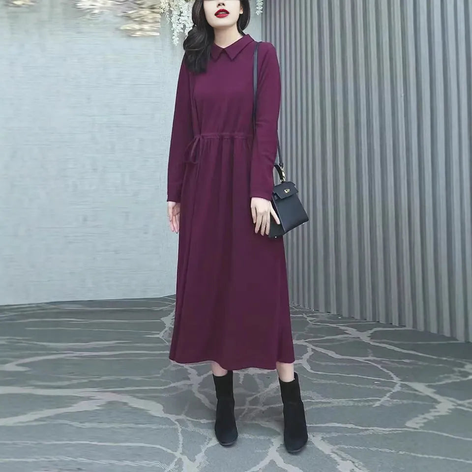 Purplish red long sleeve dress for women on a hanger, showing long skirt and extra long sleeves.