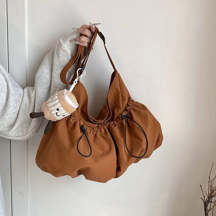 Pleated foldable polyester crossbody student bag in multiple colours showing split pocket and compact 35cm dimensions