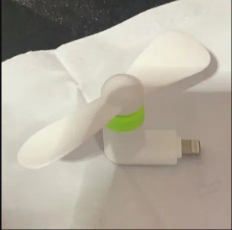 Portable mobile phone mini fan with plastic blades in various colours attached to smartphone
