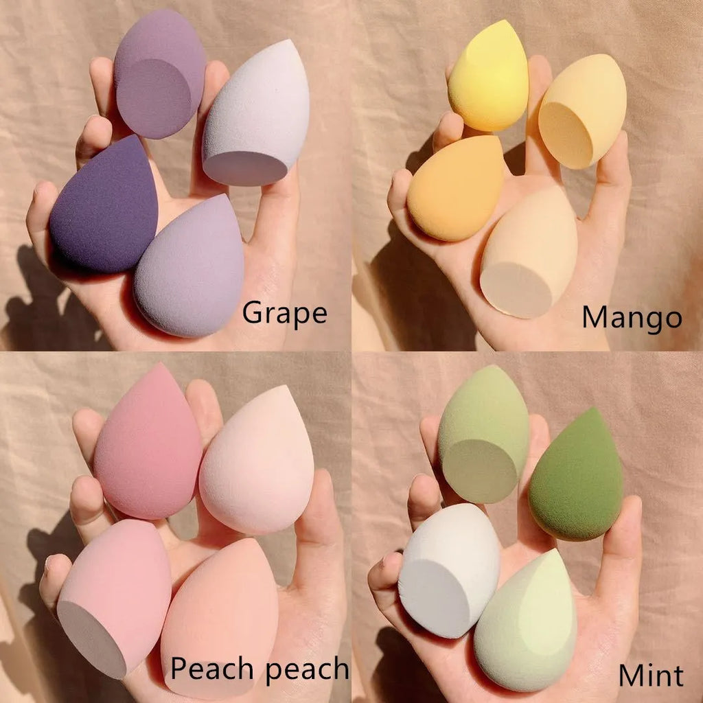 Four egg-shaped makeup sponges in grape, mango, mint, and peach colours arranged together