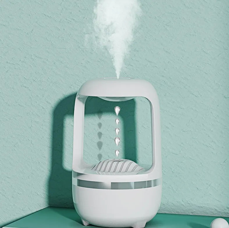 White anti-gravity humidifier showing floating water droplets on a desk next to a USB cable.