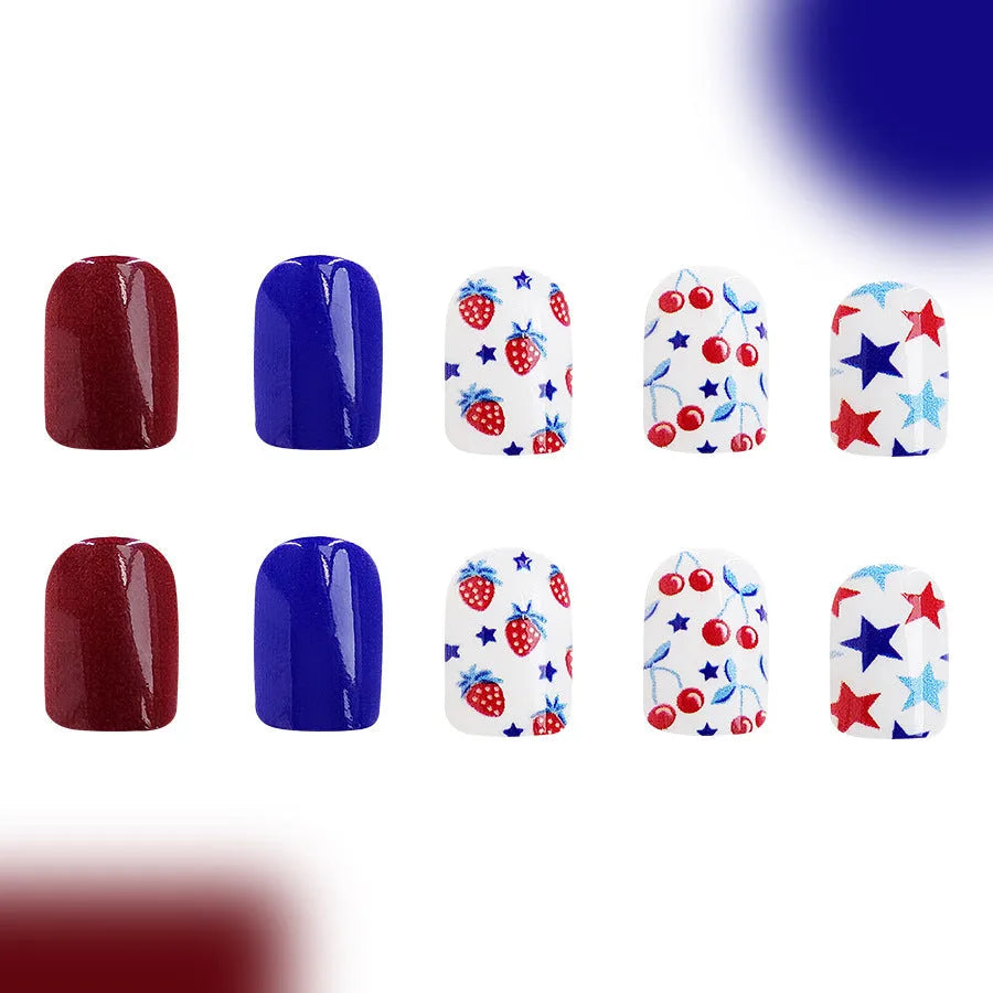 Short glossy false nails with strawberry and cherry pattern on red and blue background.