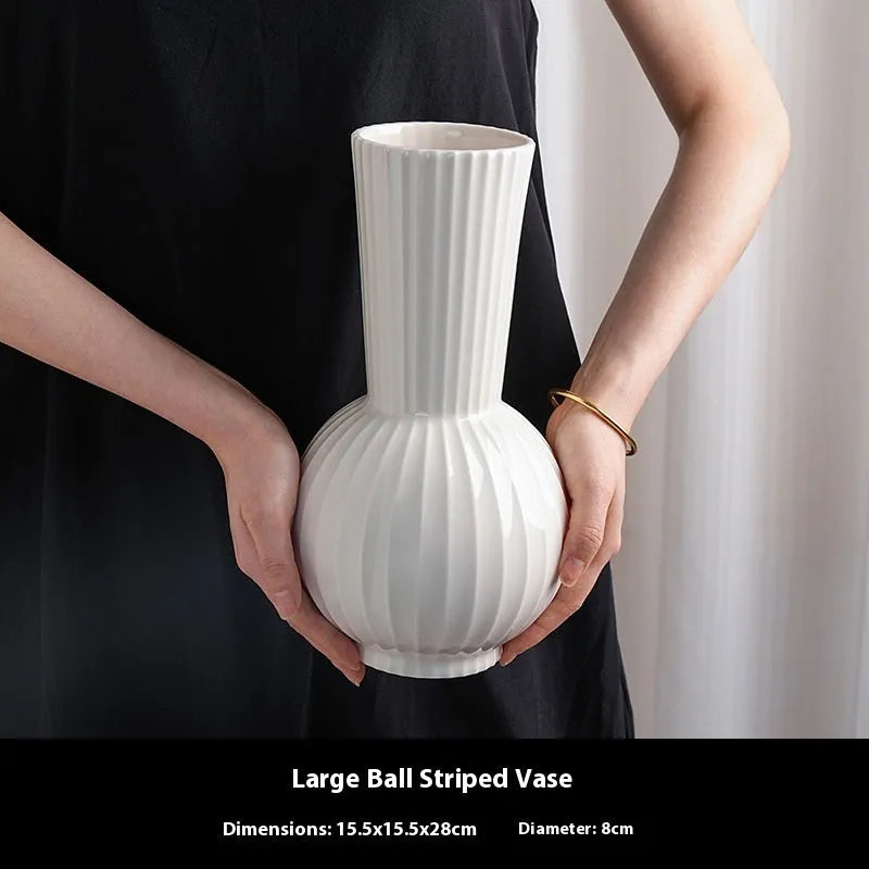 White ceramic ball vase with blue stripes on wooden table