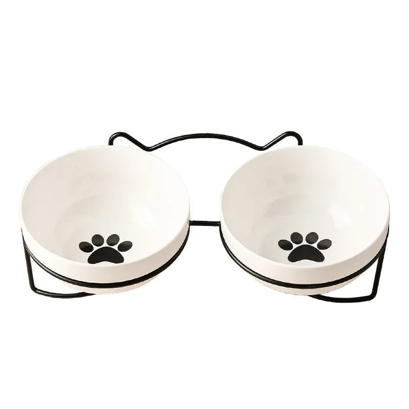 White ceramic pet bowl with cat footprints design in a black iron frame.
