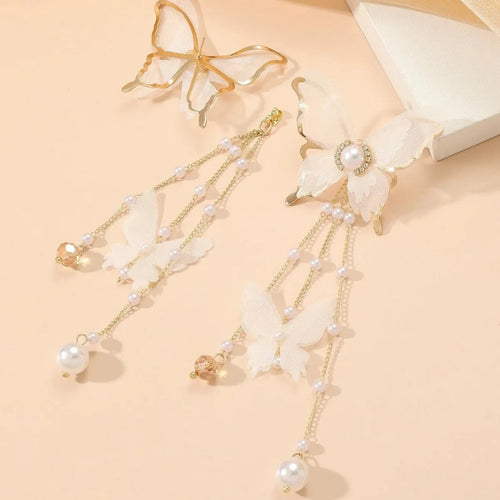 A pair of white butterfly-shaped earrings with pearls, rhinestones, and a dangling lace tassel.