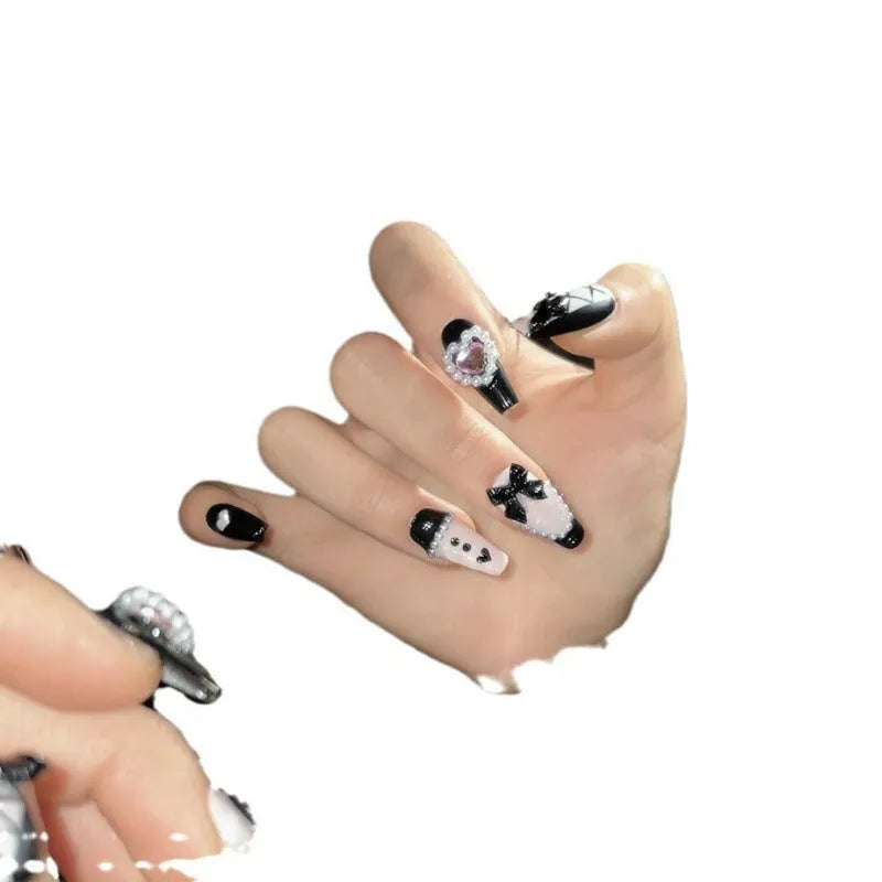 Hand-painted black and peach heart-shaped press-on nails with a cat's eye shine, shown in a set.