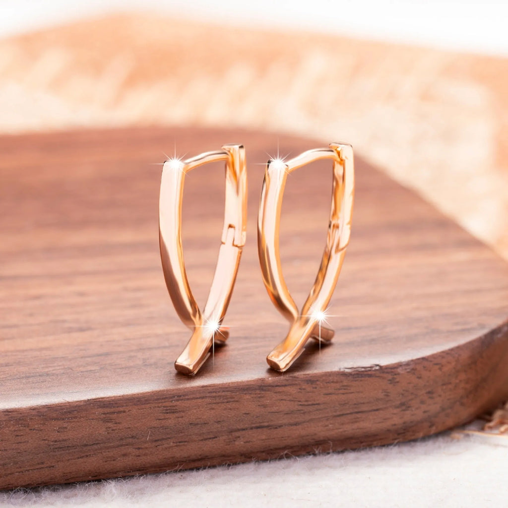 Rose gold plated cross-shaped drop earrings on a copper base.
