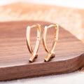 Rose gold plated cross-shaped drop earrings on a copper base.