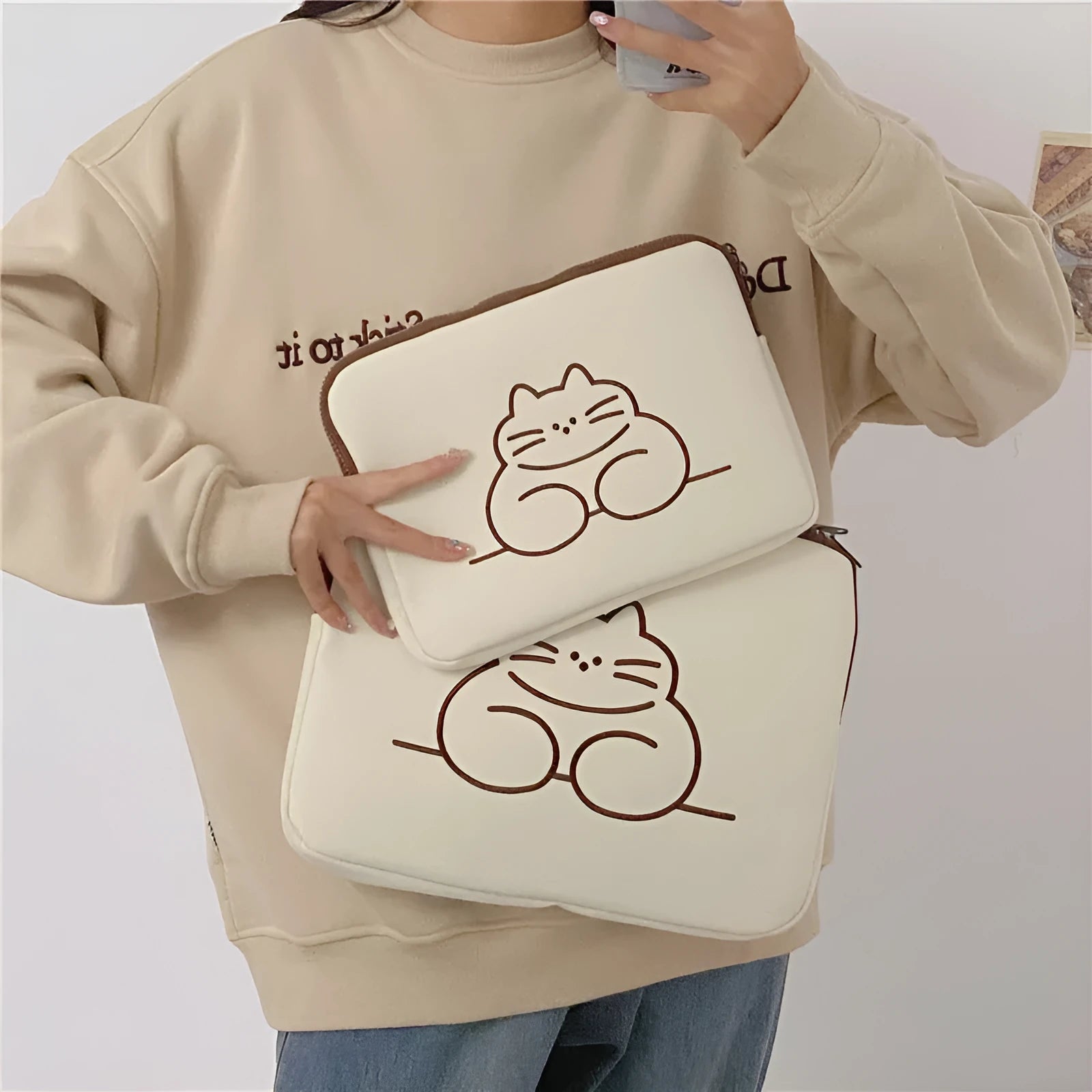 Embroidered fat cat design on a navy blue nylon laptop sleeve with a black zip
