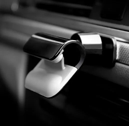 Black gravity car phone holder with 360-degree rotating head mounted on a car dashboard