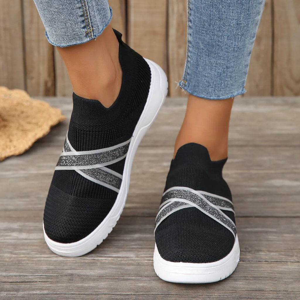 Black women's casual trainers with flyknit mesh upper, flat rubber sole, round toe, and a tassel detail.
