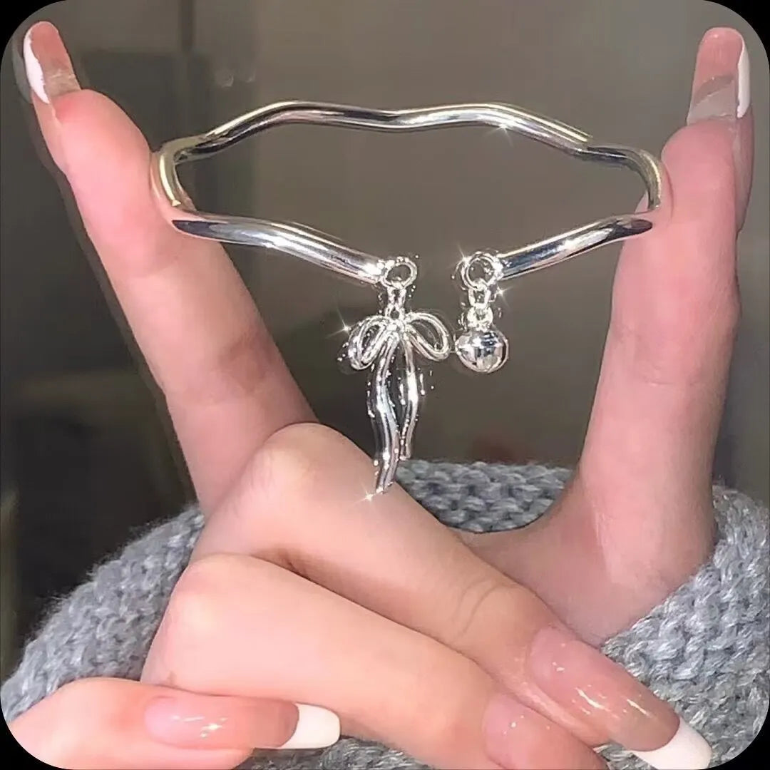 Silver bow charm adjustable bracelet with electroplated finish and bell opening mechanism