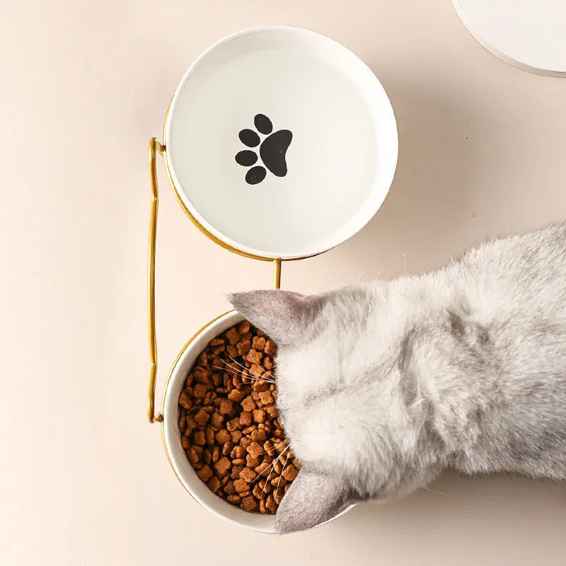 White ceramic pet bowl with cat footprints design in a black iron frame.