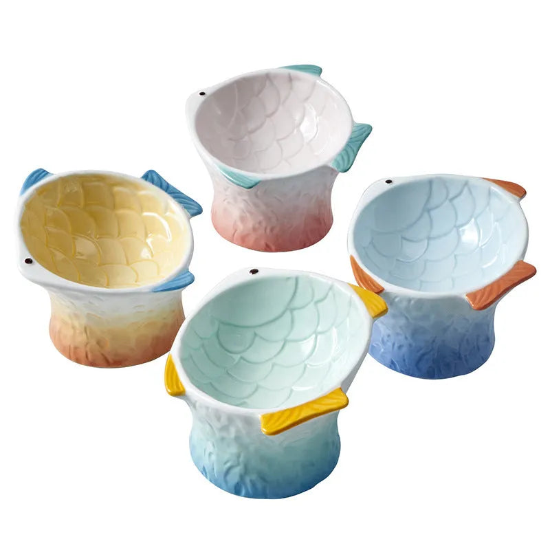 Blue fish-shaped ceramic cat feeder bowl with shallow tilt angle and non-slip base on a wooden surface.