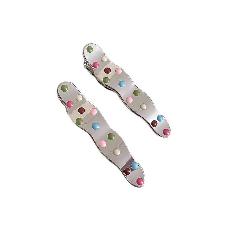 Two shiny silver metal duckbill barrettes with hollow star patterns on a plain background