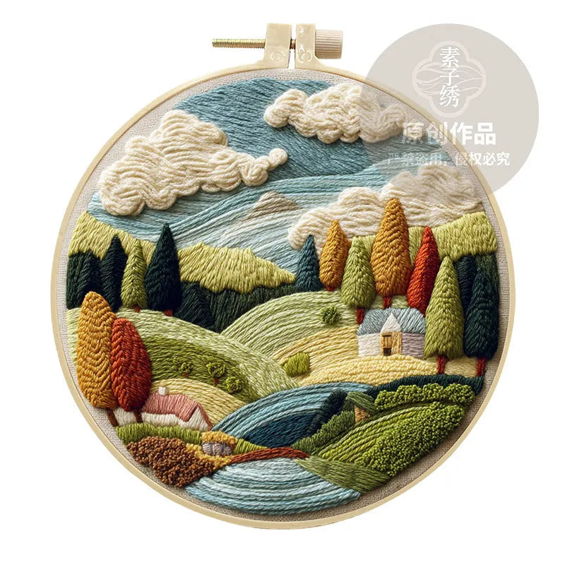 Embroidery DIY kit with bamboo frame, cotton fabric printed with a landscape scene, threads, and needles laid out
