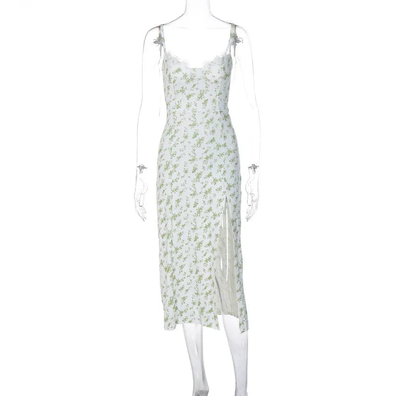A woman wearing a long blue dress with a lace floral print, a side slit and thin suspender straps.