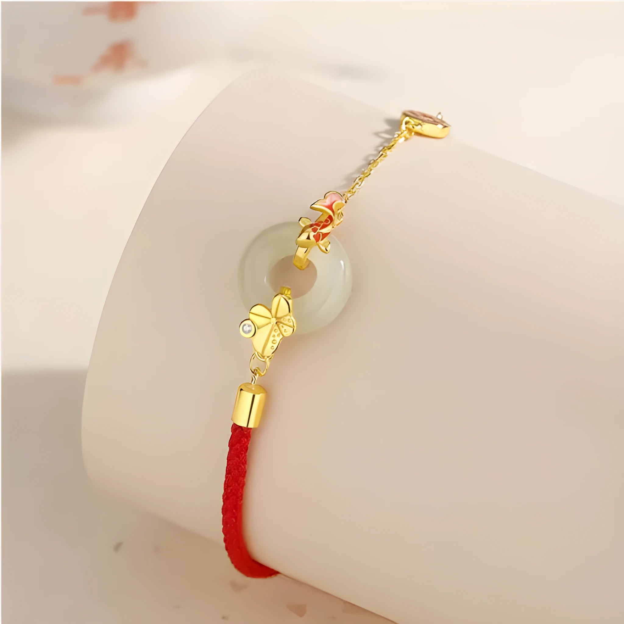 Women's silver bracelet with gold peace buckle and koi fish charm on a red rope.