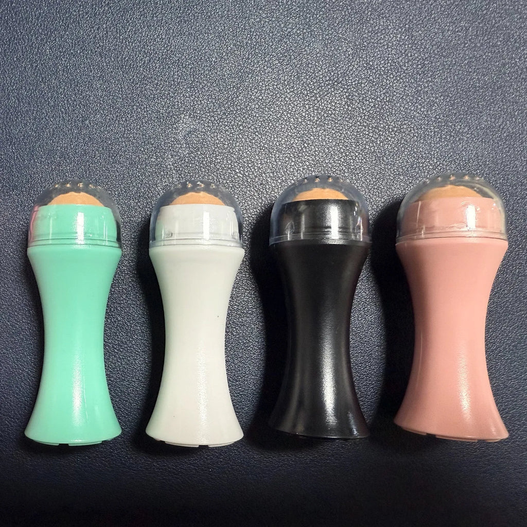Portable black volcanic stone roller for oily skin control on a pink background.