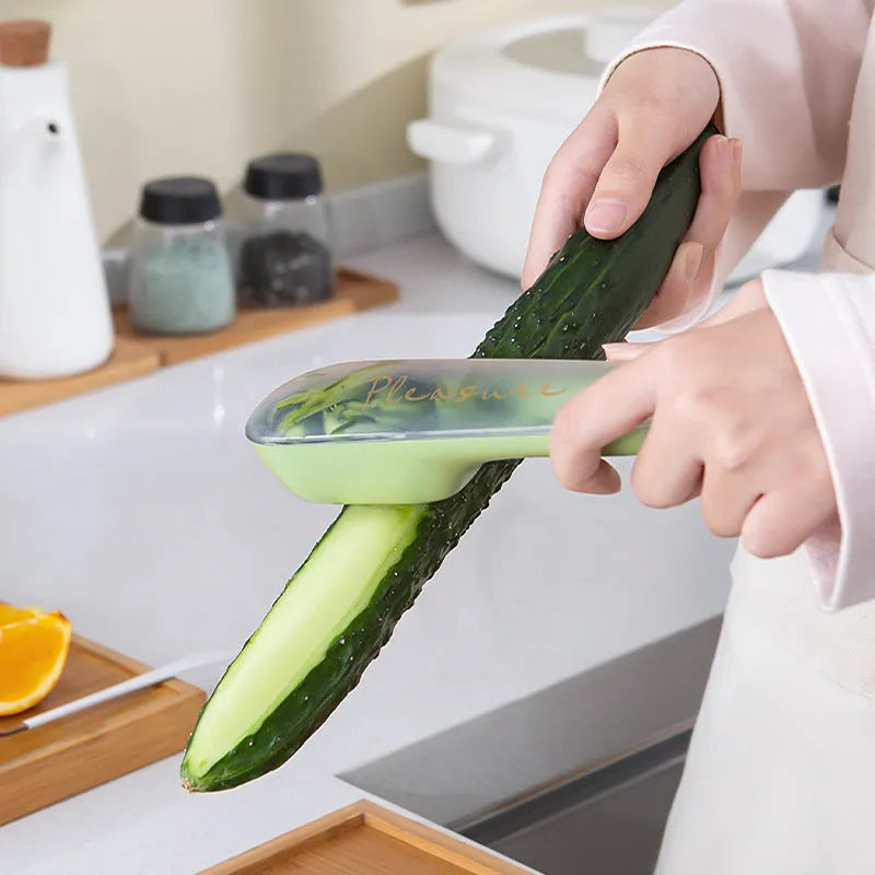 Dark green vegetable peeler with a storage tube and a stainless steel blade on a kitchen worktop.