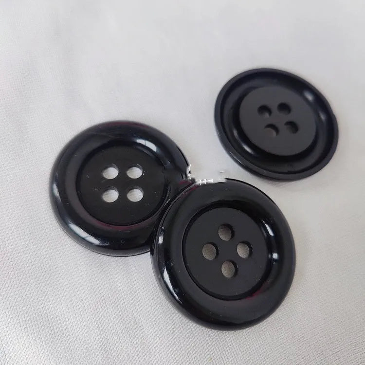 Assortment of oversized round plastic buttons in multiple colours with four stitching holes.