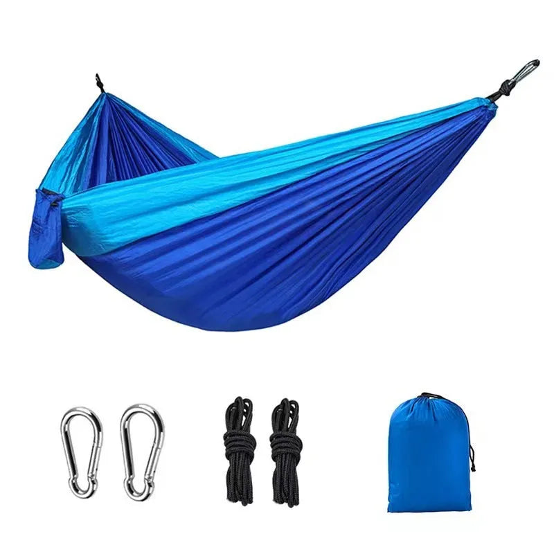 Blue parachute nylon camping hammock hung between two trees, showing its full 270cm length.