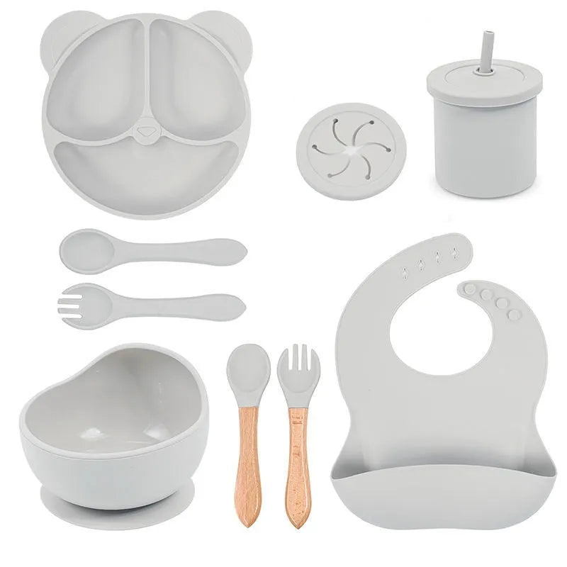 Children's silicone tableware set with cat ear cup in beige, blue and other colours on a table