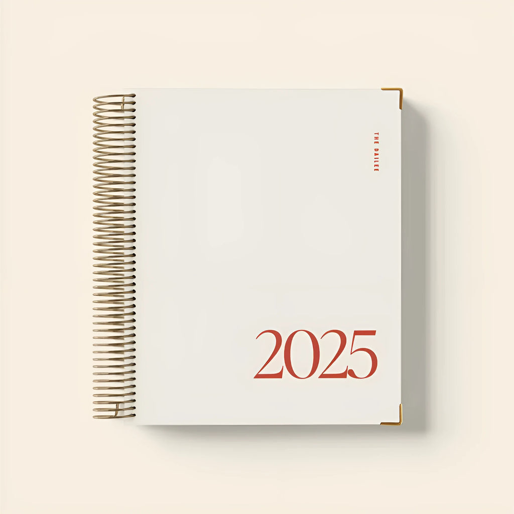Cherry red coil notebook open to daily schedule pages showing spiral binding