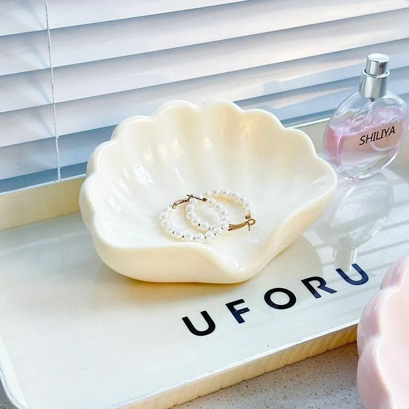 White or pink plastic shell-shaped soap dish for bathroom use.