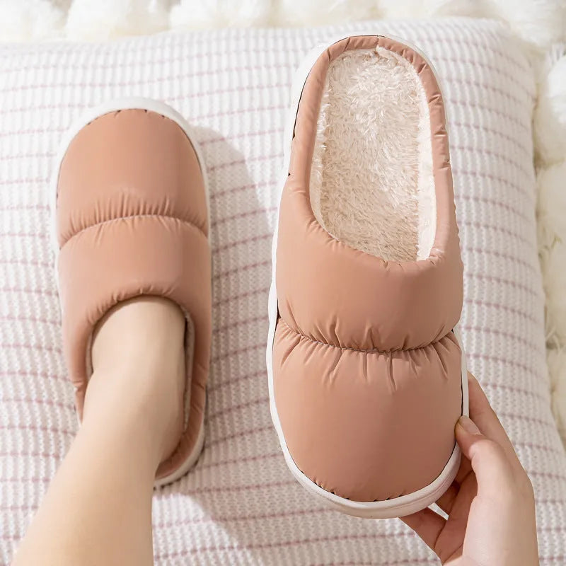 Pair of thick-soled indoor slippers in blue with a wrapped toe, low heel, and artificial plush lining.