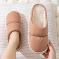 Pair of thick-soled indoor slippers in blue with a wrapped toe, low heel, and artificial plush lining.