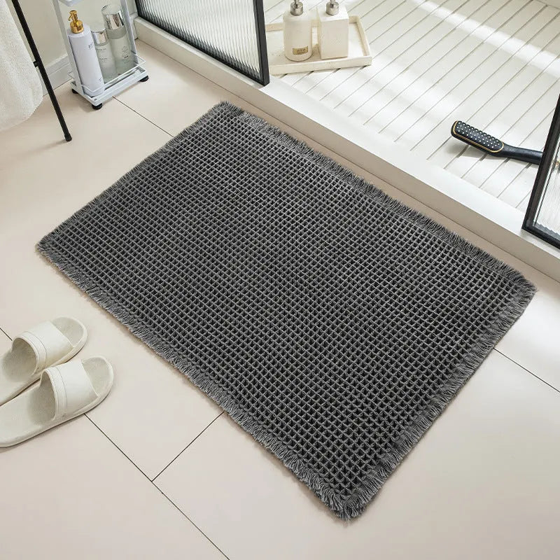 A square, checkered-pattern absorbent bathroom floor mat with a non-slip backing, shown in a neutral colour.