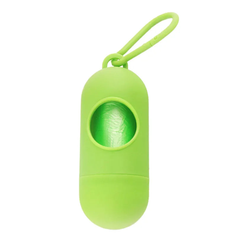 A compact black dog poop bag holder with a side hook and Velcro strap, shown next to a roll of waste bags.